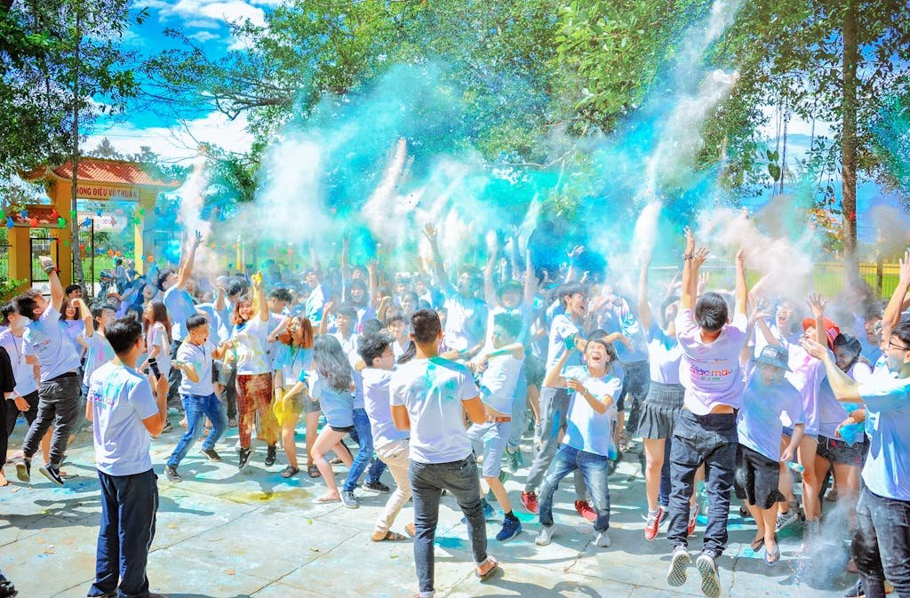 Home Energetic crowd enjoying a vibrant outdoor festival with colorful powder at daytime.